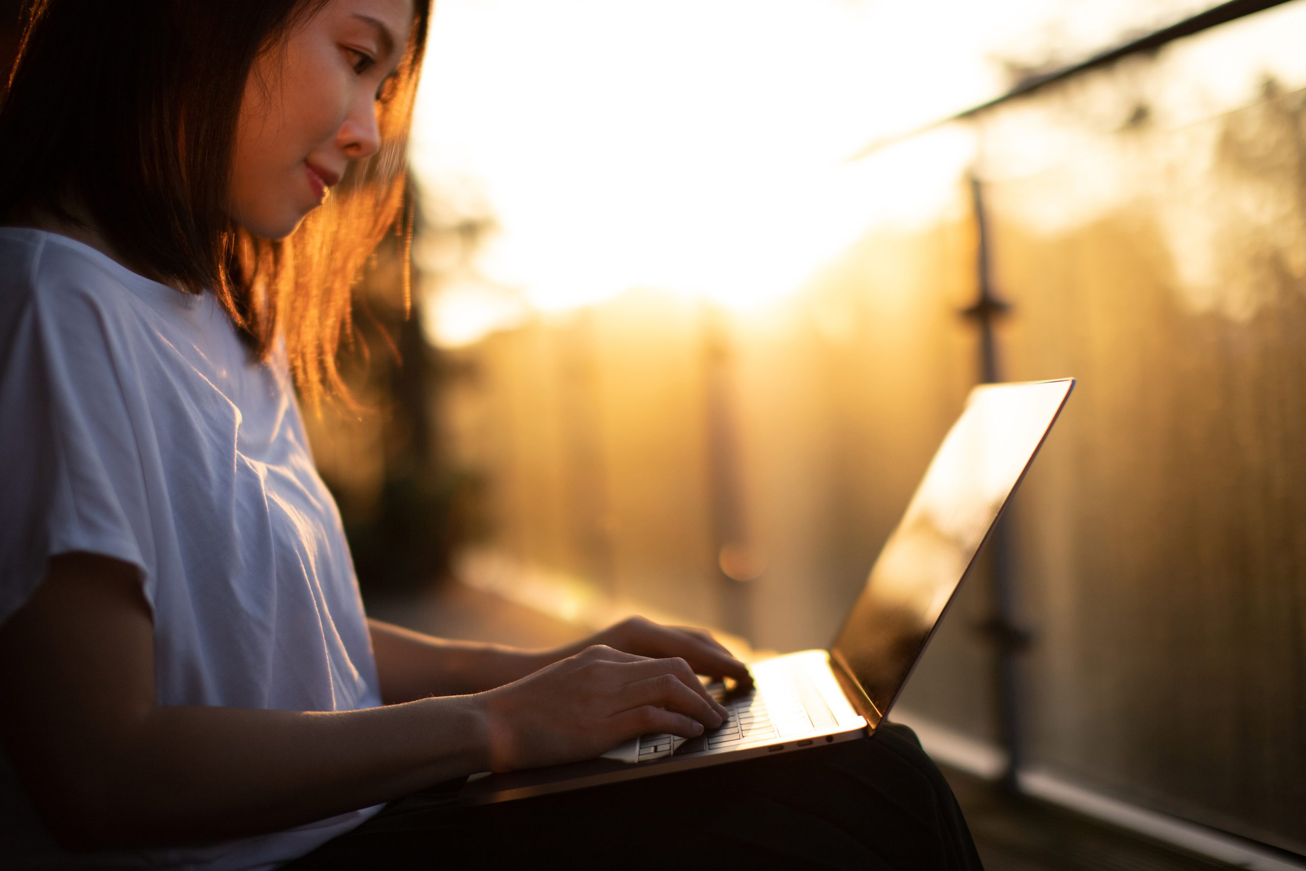 Cropped Shot Of Young Woman Working With Laptop On The Balcony